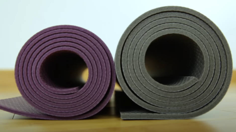 Two rolled yoga mats, one purple and one green, with varying thickness.