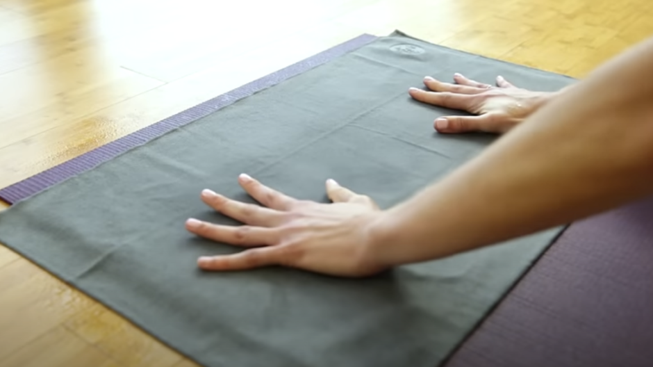 Gray towel placed on top of a yoga mat.
