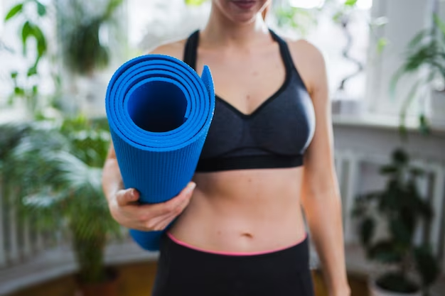 A woman showcasing the thickness of a rolled blue yoga mat she's holding