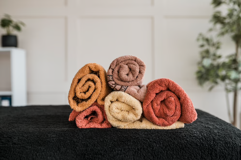 Image of rolled towels in various colors placed on a table covered with a black towel
