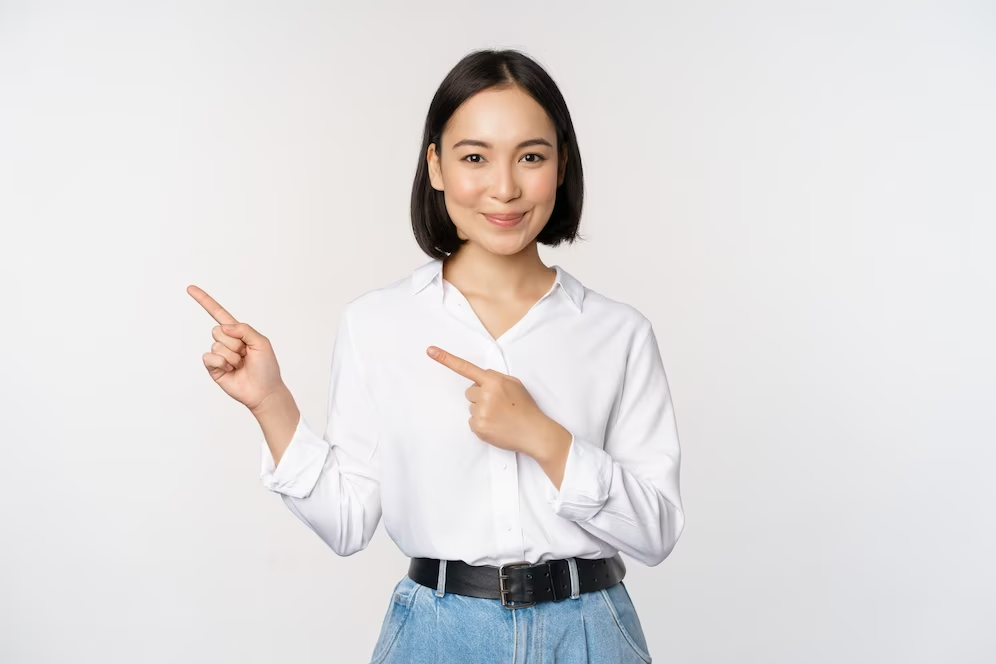 Image of a girl with short hair wearing a white polo, pointing both hands to the left side