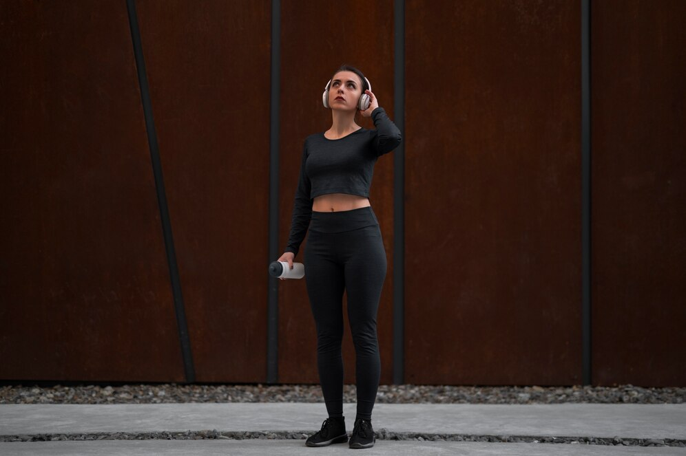 Woman wearing a full black yoga outfit and a headset